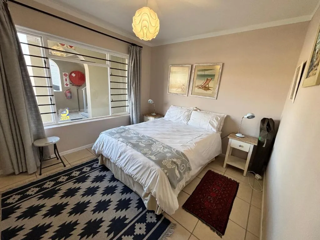 Second bedroom with a queen bed and framed beach deck-chair prints above the headboard