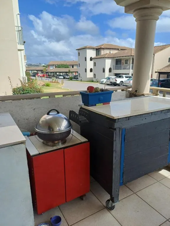 Covered balcony with a built-in braai station and kettle braai overlooking the complex