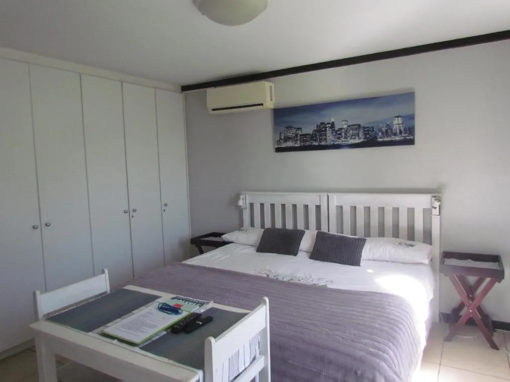 Bedroom with white built-in wardrobes, a wall-mounted air conditioner and a small writing desk