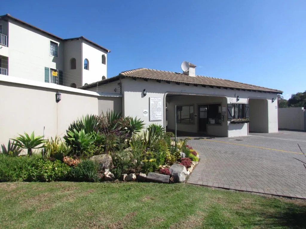 Complex entrance with a tiled gatehouse roof, reception office and a landscaped succulent bed