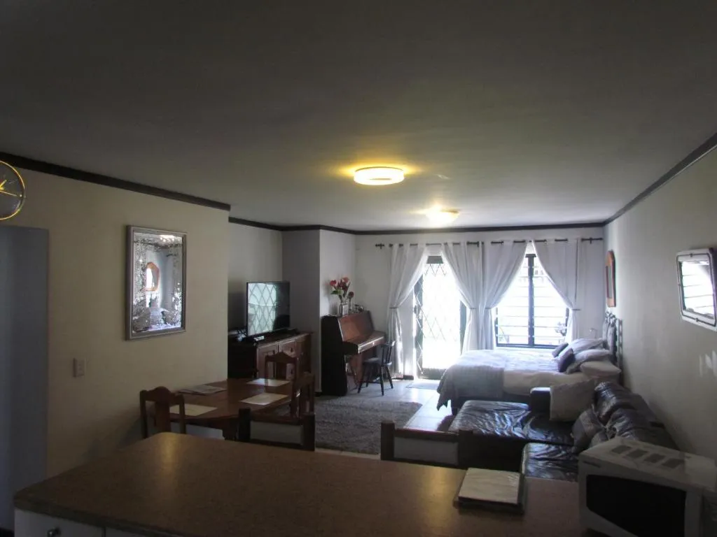 Open-plan lounge and dining area with a piano, leather sofa and a four-seat dining table