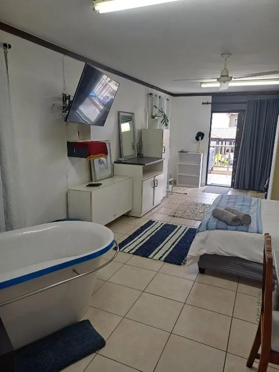Open-plan studio combining the bed with a freestanding bathtub and wall-mounted TV
