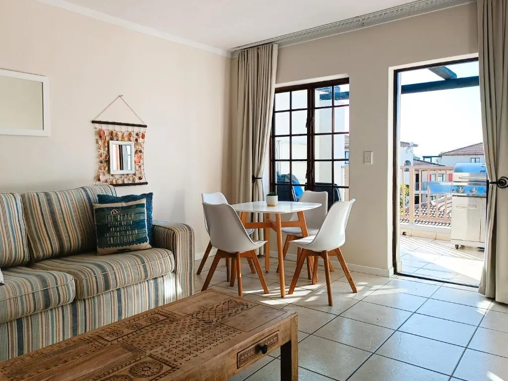 Living area with dining table and sliding doors onto a balcony fitted with a gas braai