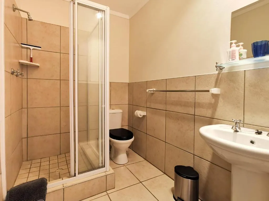 Bathroom with corner shower, pedestal basin and tiled walls