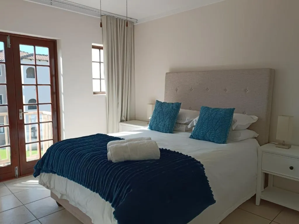 Bedroom with teal cushions and French doors opening onto a balcony over the estate