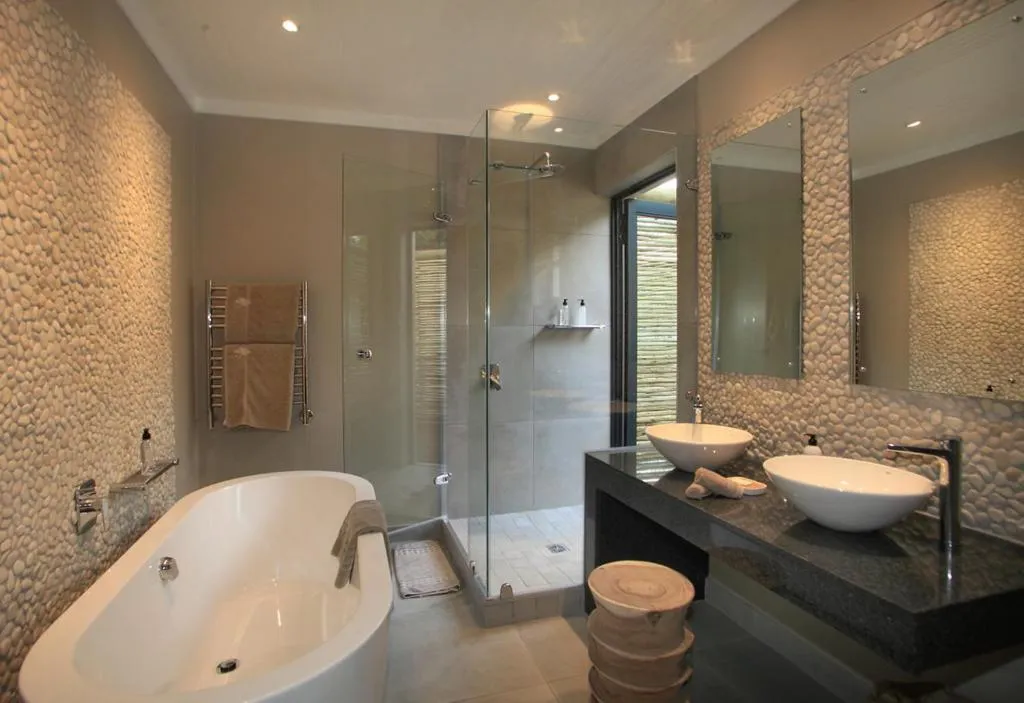 Bathroom with a freestanding tub, double vessel-sink vanity and pebble-tiled walls