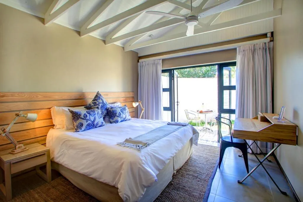 Bedroom with an exposed timber ceiling and glass doors opening onto a private outdoor table
