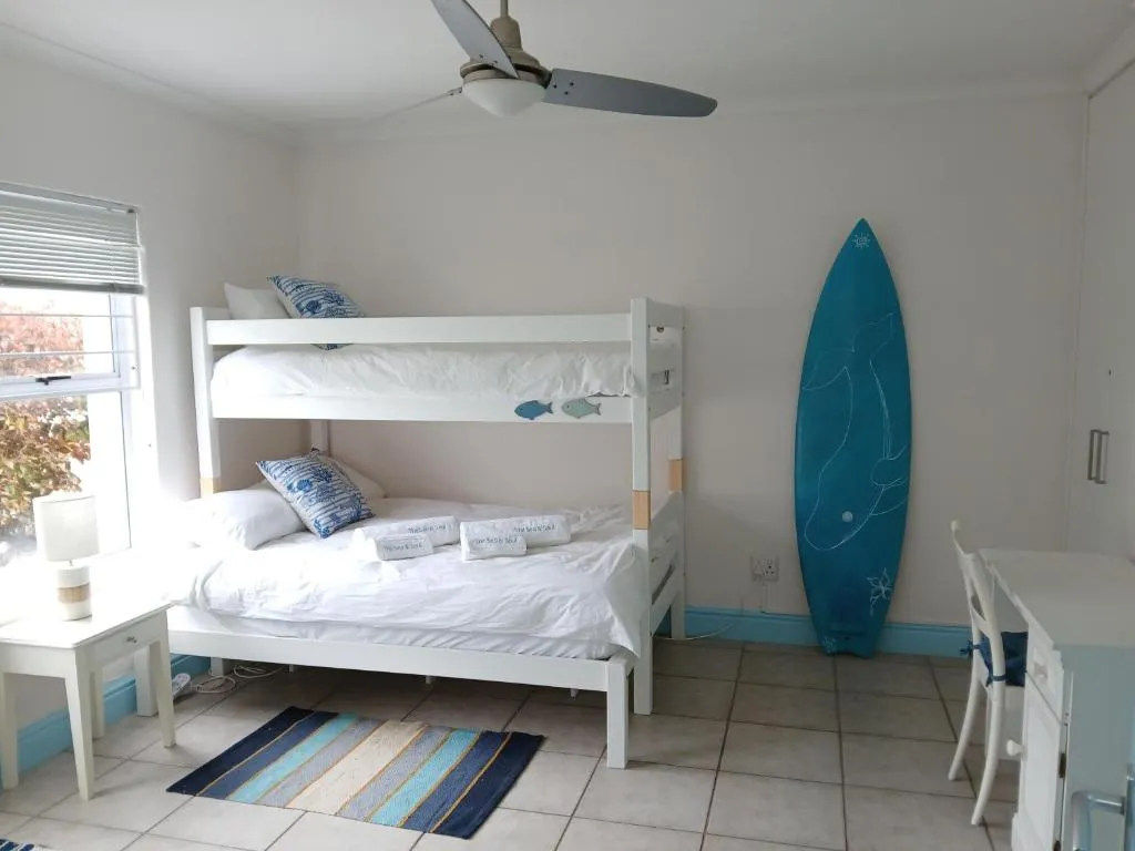 Bunk bedroom with a surfboard leaning in the corner and a study desk