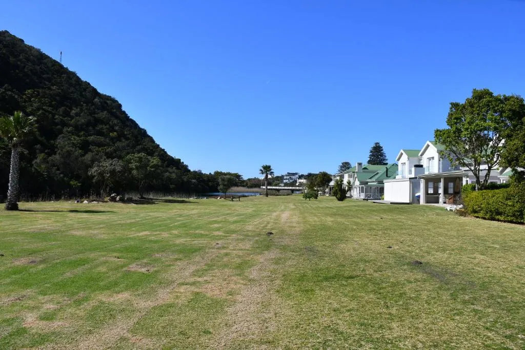 Open estate lawn running down toward the river with houses along the edge