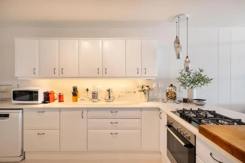 Galley kitchen with white cabinetry, gas hob, built-in oven and dishwasher