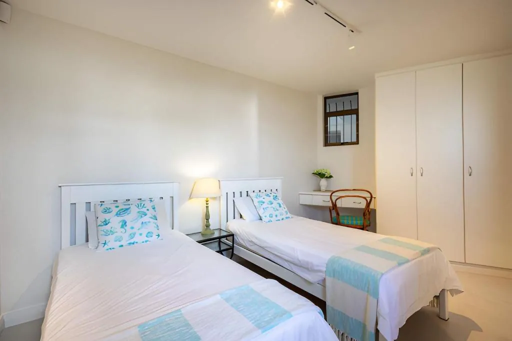 Twin-bed bedroom with fitted white wardrobes and a small work desk