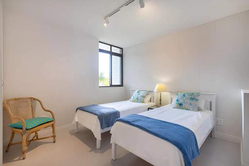 Twin-bed bedroom with a rattan armchair and a tree-facing window