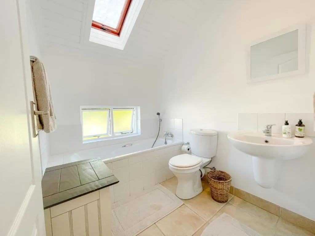 Bathroom with a built-in bath, skylight and a wall-mounted basin
