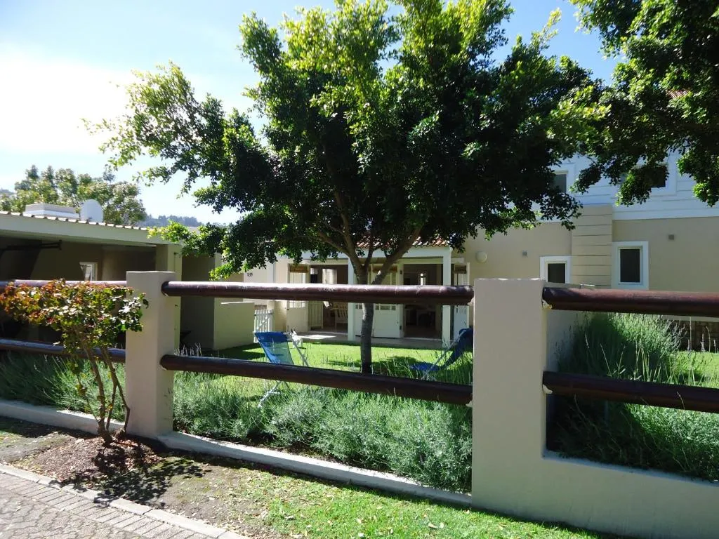 Complex garden entrance with a tree, lawn and neighbouring units seen over a low wall