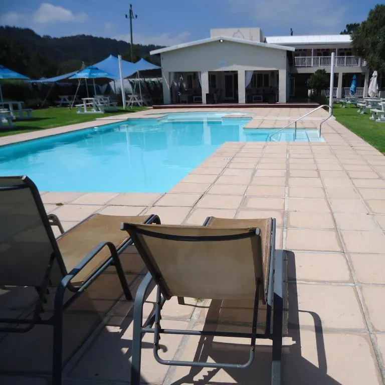 Shared resort-style pool with sun loungers, umbrellas and a clubhouse building on the estate