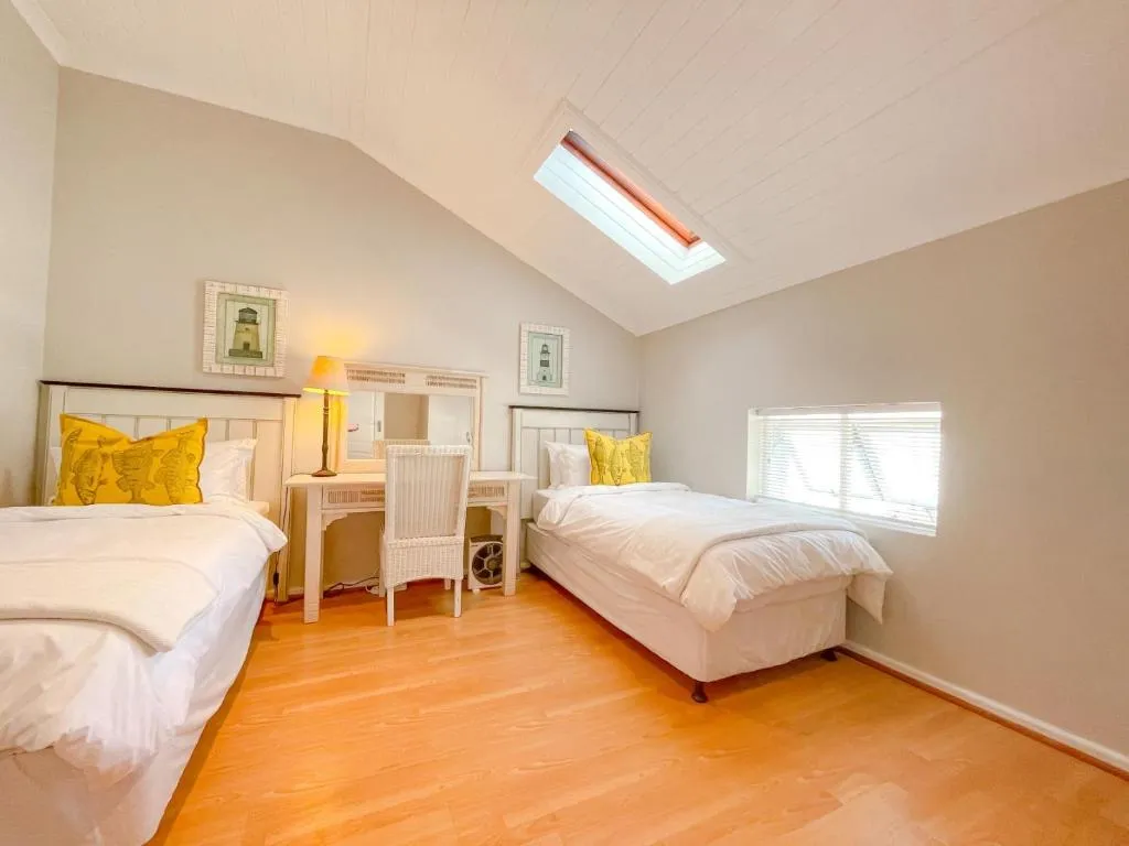 Twin bedroom under a sloped ceiling with a skylight and a shared writing desk