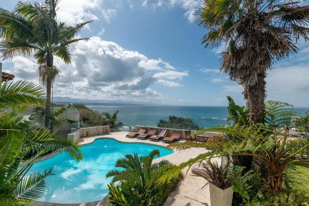 Swimming pool with loungers set against an open ocean backdrop