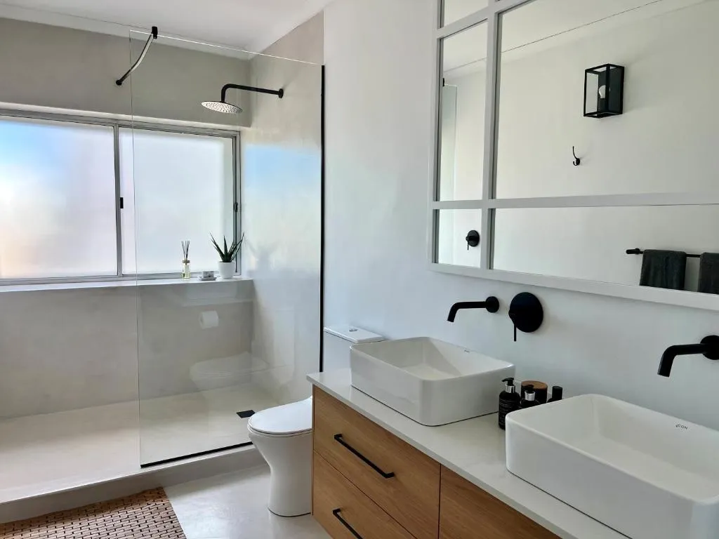 En-suite bathroom with double vessel sinks, a walk-in glass shower and freestanding toilet