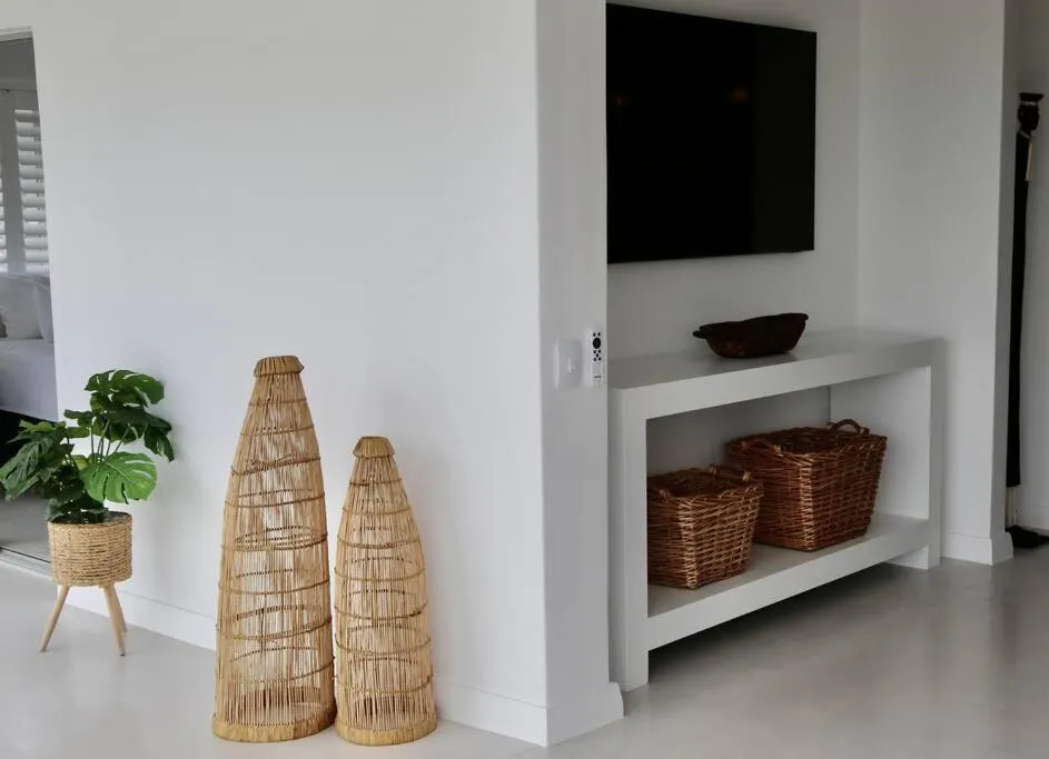 Hallway nook with a wall-mounted TV, woven baskets and tall rattan floor vases