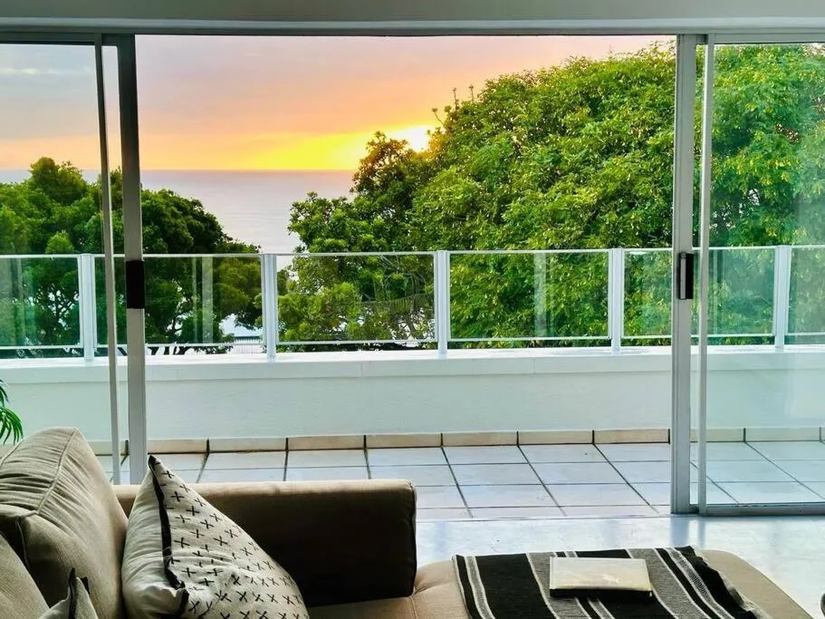Living room sofa facing open sliding doors onto a tiled terrace with a sea view sunset