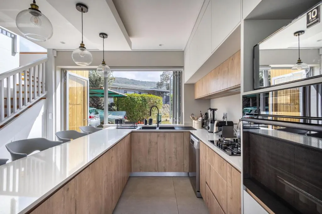 U-shaped kitchen with quartz counters, gas hob and pendant lights over a breakfast bar