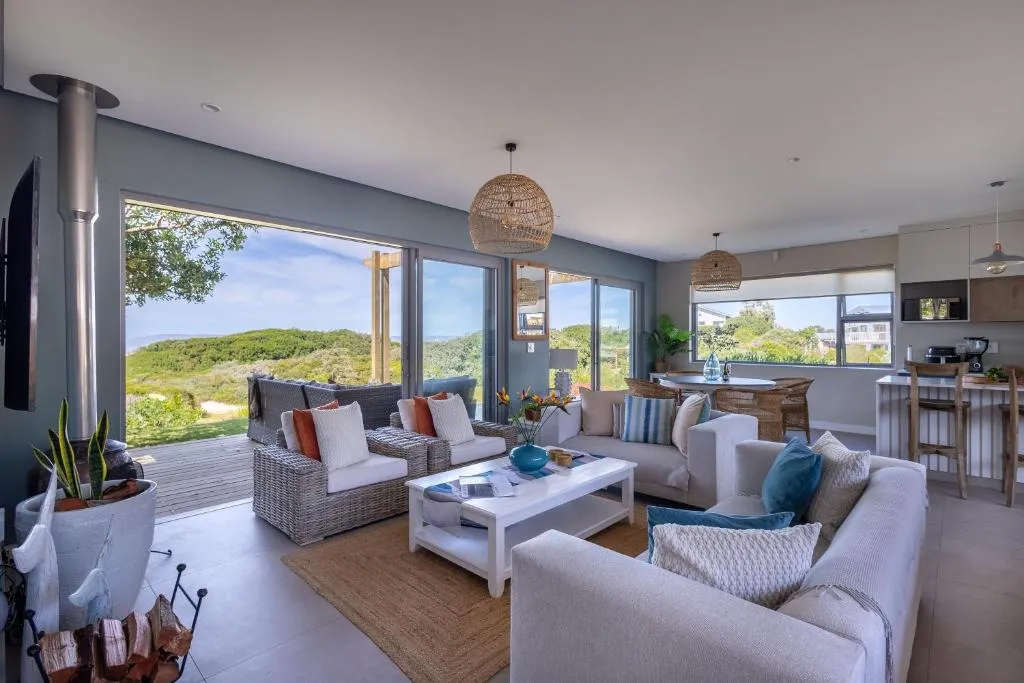 Open-plan living and kitchen area with sliding doors onto a deck ringed by dune vegetation