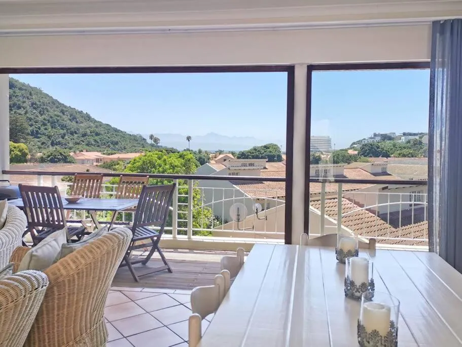 Balcony terrace with outdoor dining table and chairs looking out over the hills toward the bay