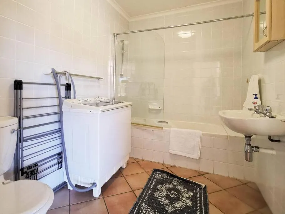 Bathroom with bath, shower, twin-tub washing machine and terracotta tiled floor