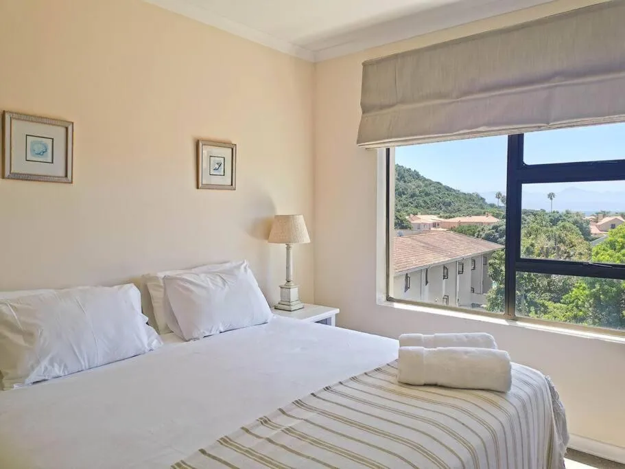 Bedroom with double bed and a window view over red-tiled rooftops toward the hills