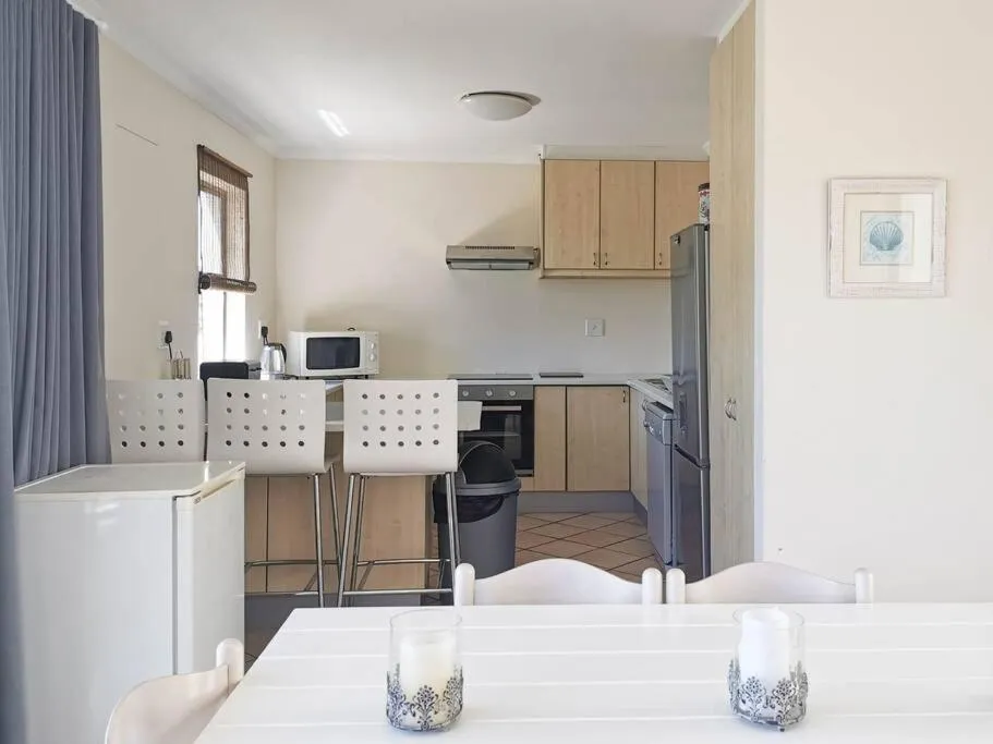 Kitchen with breakfast bar stools, oven, extractor fan and fridge freezer, open to the dining table