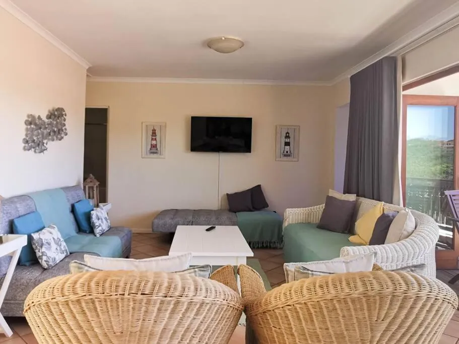 Second seating area with wicker armchairs, sofas and a wall-mounted TV facing folding balcony doors