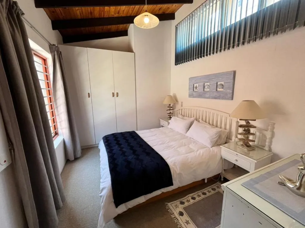 Bedroom with a vaulted wood-beam ceiling, white built-in wardrobes and a double bed