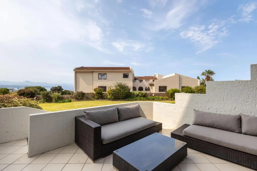Private balcony with wicker lounge seating overlooking neighbouring rooftops and gardens