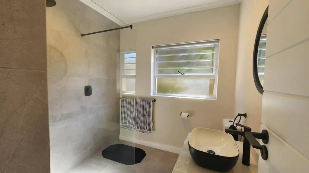 Walk-in shower and freestanding vanity in a tiled bathroom with a grab rail