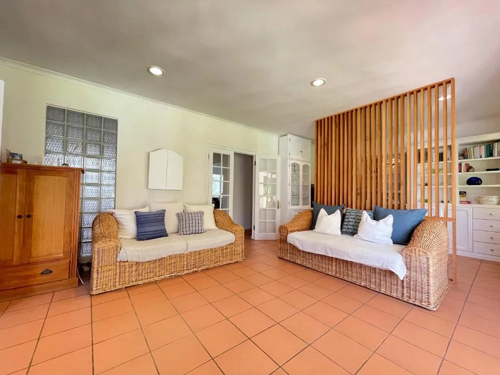 Tiled living room with two wicker sofas and a slatted timber room divider