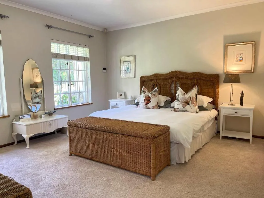 Main bedroom with a wicker headboard, king bed and garden-facing window