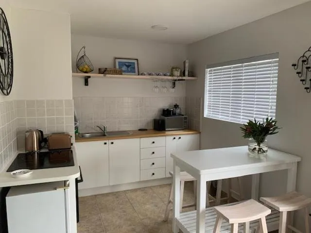 Compact kitchenette with white cabinetry, stovetop, and a small dining table