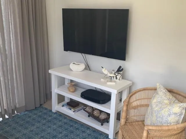 Second view of the lounge with wall-mounted TV console and wicker armchair