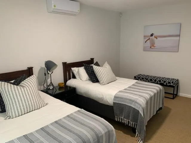 Twin bedroom with striped bedding, wall-mounted air conditioner, and a penguin print
