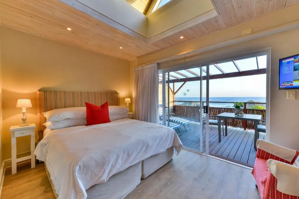 Bedroom with a red accent cushion and glass doors opening onto a private ocean-view deck
