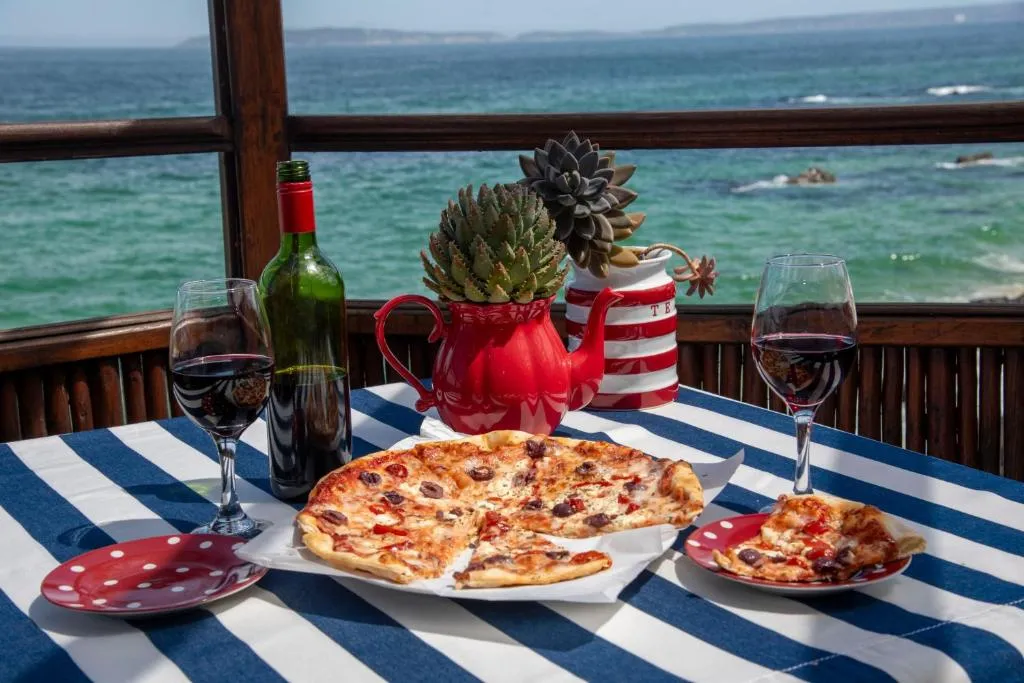 Table set with pizza, wine and succulents on a deck overlooking the ocean