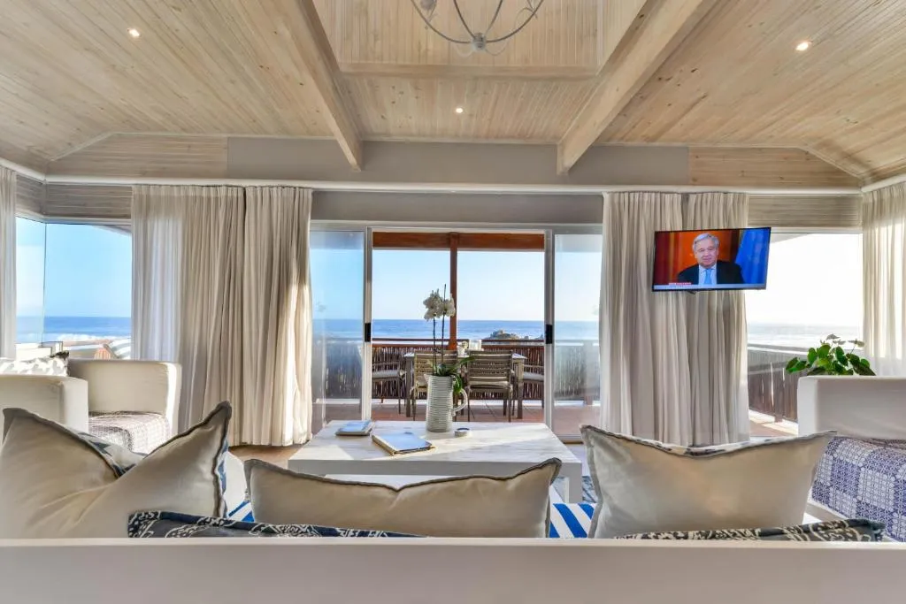 Living room with a wall of glass doors opening onto an ocean-view balcony at Keurboomstrand