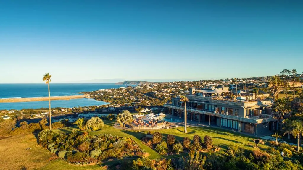 Aerial view of the hillside villa with a landscaped pool terrace overlooking the bay and coastline