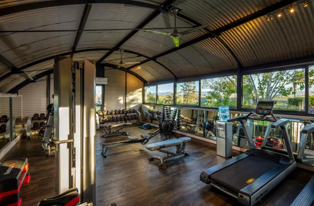 Fitness room with treadmills, free weights and a rowing machine under a curved roof