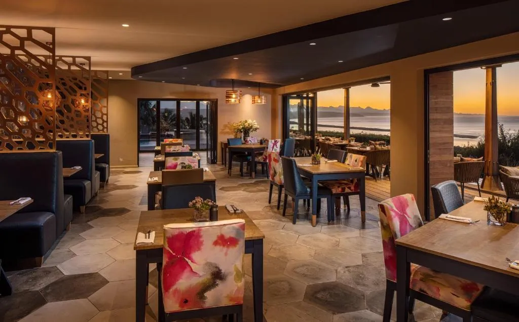 Open-plan restaurant with sunset views over the lagoon through floor-to-ceiling doors
