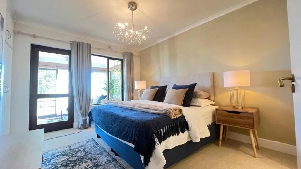 Bedroom with navy bedding, a crystal chandelier, and glass doors onto a private balcony