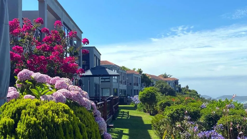 Garden walkway lined with pink hydrangeas and bougainvillea leading past the estate's apartment blocks