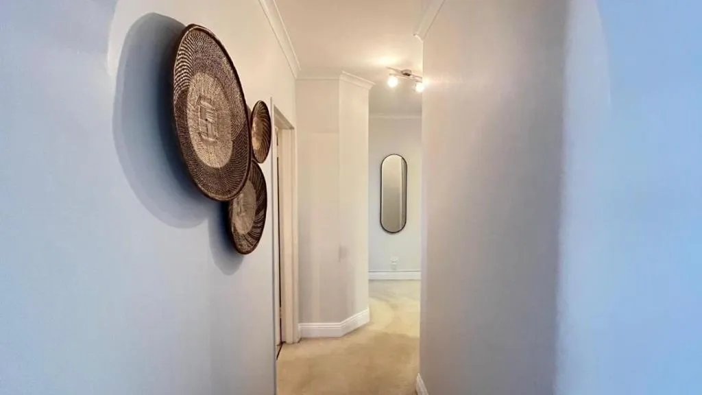 Hallway with woven African basket wall art and a full-length mirror