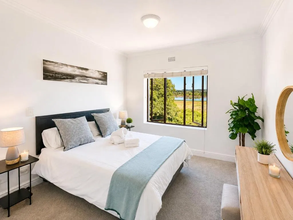 Bedroom with a double bed and a window framing the Keurbooms lagoon and greenery