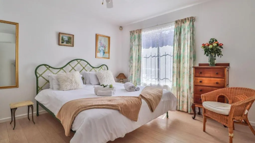 Bedroom with a wrought-iron bed frame, floral curtains and a barred window over the courtyard